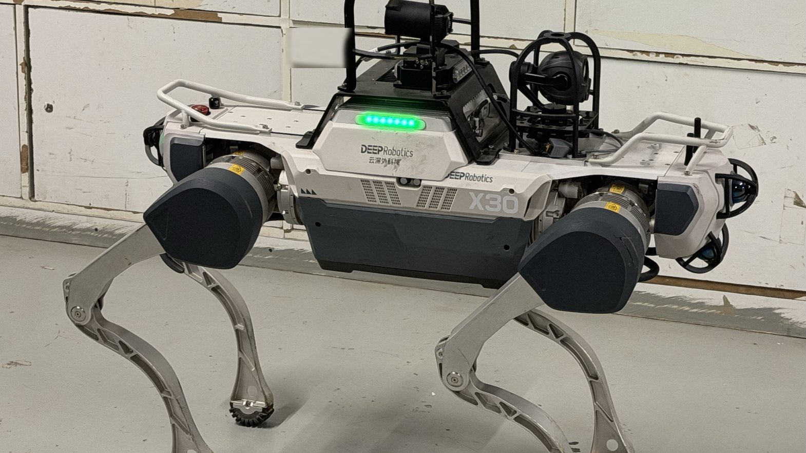 Deep Robotics X30 quadruped inspection robot with pan-tilt camera head, operated by WOLKER Robotics on a site in Abu Dhabi, September 2026